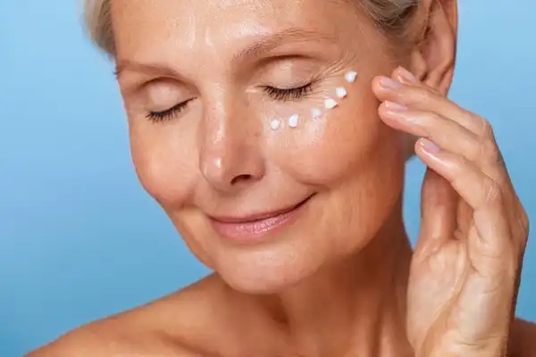 Dojrzała kobieta nakłada krem pod oczy